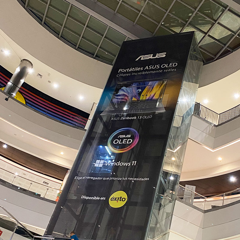 Gigantografía en banner impresa en banner microperforado con tintas ecosolventes, instalada en cubierta trasera de vidrio de ascensor centro comercial.